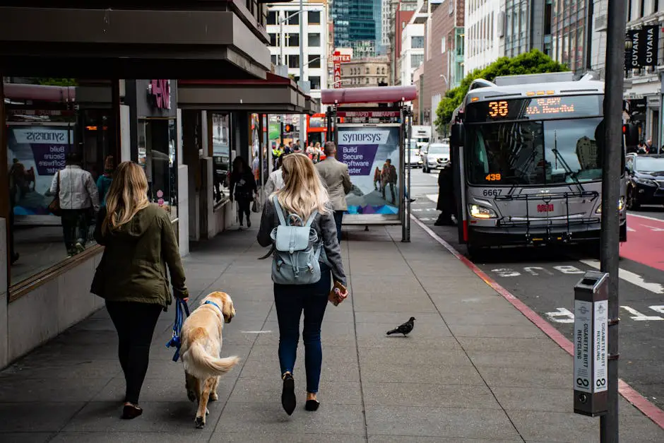People walking on a bustling city sidewalk with a bus on the street, showcasing urban life.