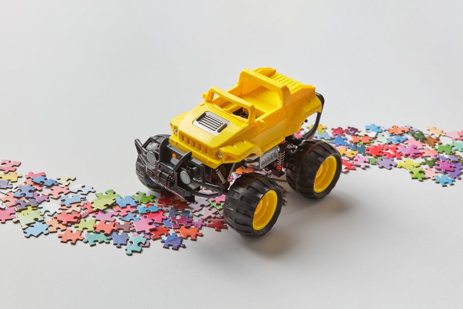 A yellow toy truck navigates on a colorful jigsaw puzzle path, creating a playful scene.